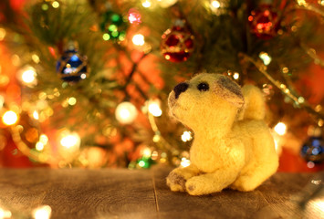 Symbol of new years 2018 yellow dog. Bolt. New years greetings background. Fancy handmade toy from wool on bokeh Christmas background. Copyspace for congratulations.