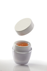 blank white jar with gel and flying lid on white background