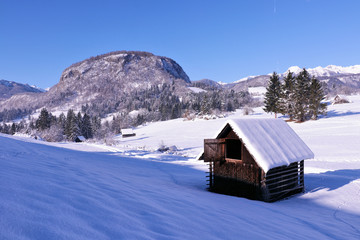 small barns with hill behind in winter time