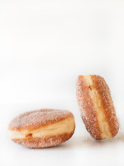 German fried donut, so called Krapfen, Berliner or Pfannkuchen, filled with rose hip jam and dusted with cinnamon sugar, traditionally eaten at carnival and at New Year's Eve on white background