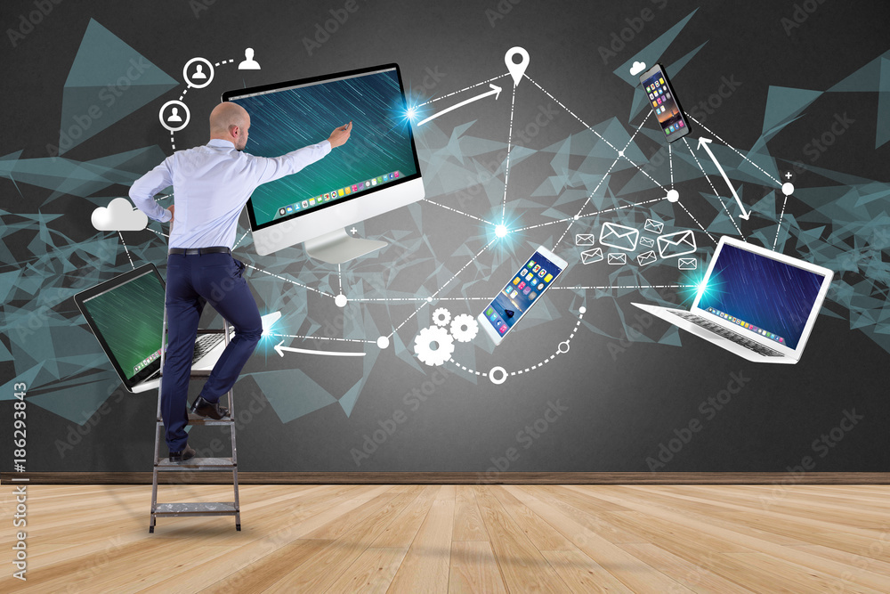 Poster businessman in front of a wall with computer and devices displayed on a futuristic interface with in