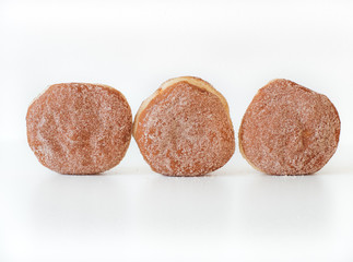 German fried donut, so called Krapfen, Berliner or Pfannkuchen, filled with rose hip jam and dusted with cinnamon sugar, traditionally eaten at carnival and at New Year's Eve on white background