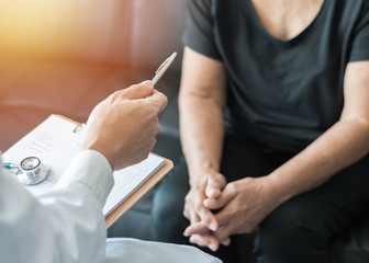 Geriatric doctor (geriatrician) consulting and diagnostic examining elderly senior adult patient (older person) on aging and mental health care in medical clinic office or hospital examination room