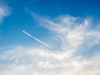 Naklejka na ściany i meble Cloudy blue sky with aircraft contrail