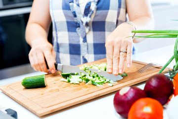 Female hands cutting cucumbers