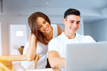 Happy modern couple working on laptop at home