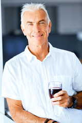 Senior man with holding a glass of wine indoors