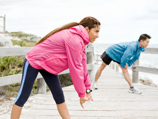Young couple at the seaside doing exercises