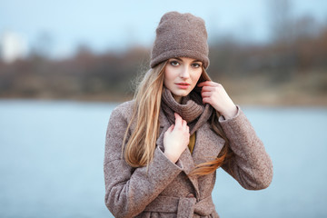 Stylish blonde woman in trendy urban outwear posing cold weather on the river bank. Vintage filter film saturated color. Fall mood concept.