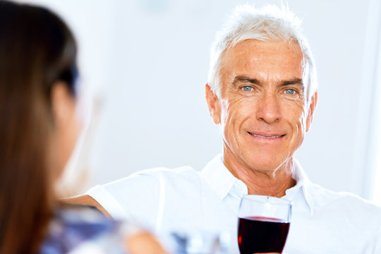 Senior man with holding a glass of wine indoors
