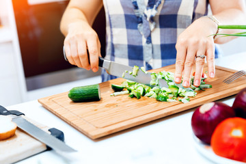 Female hands cutting cucumbers