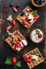 Waffles with berries on old rustic background.