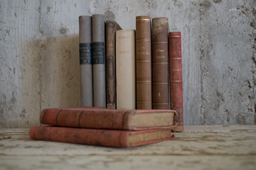libri antichi appoggiati su tavolo di legno e muro grezzo