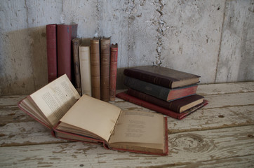 libri antichi appoggiati e aperti su tavolo di legno e muro grezzo