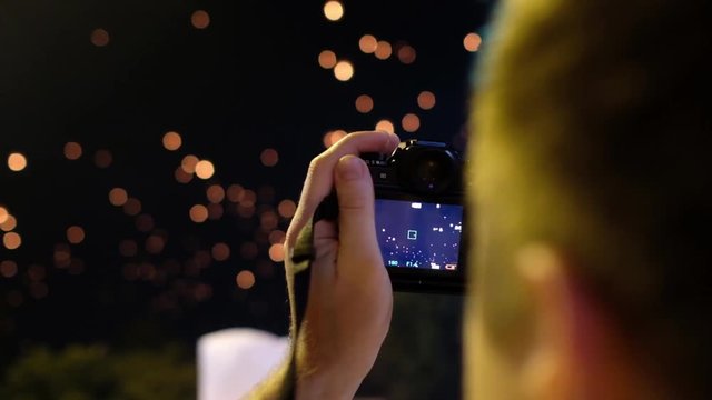 Tourist takes video of flying flaming lanterns at a holiday krathong in Chiang Mai Thailand