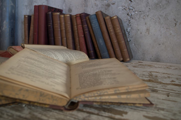 Naklejka premium libri antichi chiusi e aperti su tavolo legno e contro muro grezzo