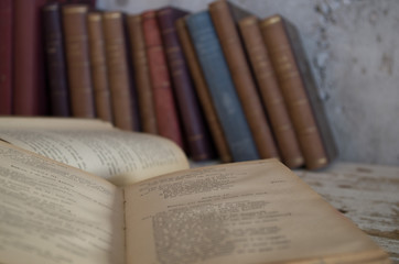 libri antichi chiusi e aperti su tavolo legno e contro muro grezzo