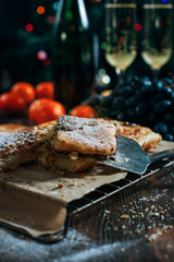a festive New Year's table, cheese cake with chocolate, tangerines, grapes, biscuits, champagne and two glasses against the backdrop of a decorated Christmas tree with lights