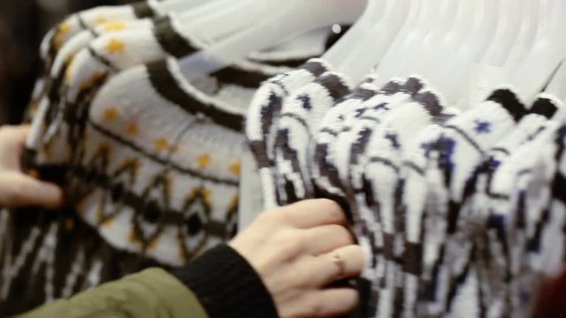 Woman choosing a pullover at shop in shopping centre
