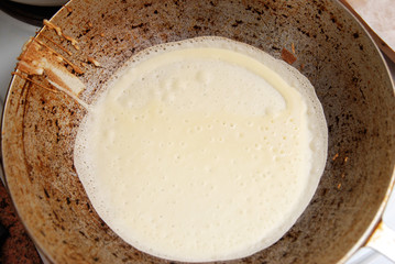 Raw pancake in a old vintage frying pan on a dark background