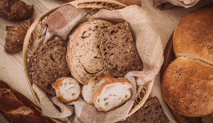 Many mixed baked breads and rolls on rustic wooden table