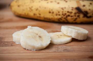 Fototapeta na wymiar banane coupée en rondelles sur planche à découper en bambou 