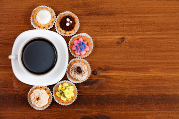 Fototapeta na wymiar Closeup shot of small cup of coffee with colorful cupcakes. Flat lay