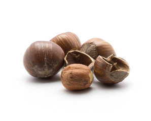 Three unshelled hazelnuts with one shelled and two hollow shell halves isolated on white background.