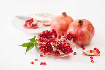 The broken pomegranate fruit with leaves on white