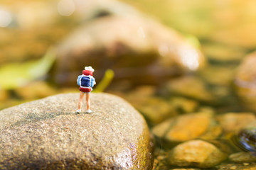 Miniature people, backpackers walking on the stones at river. Travel Lifestyle adventure vacations concept