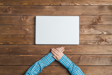 Top view of woman sitting at wooden table with hands folded