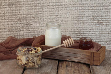 On a wooden table, muesli (granola) with milk and honey.