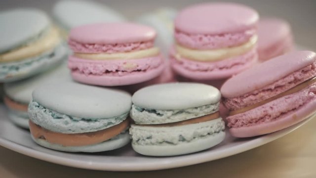 French macarons - meringue cookies with ganache or buttercream filling. Colorful macaroons rotating, horizontal view , slow motion
