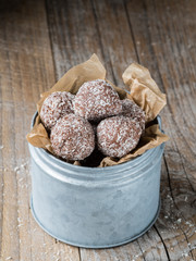 Homemade coconut and chocolate balls in baking paper and metal dose.