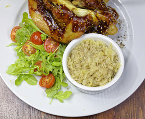 Pork knuckle with garnish on a white plate