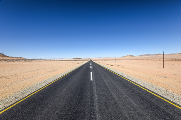 Beautiful wide angle view of the B4 road between Lüderitz and Keetmanshoop near Garub in Namibia, Africa. The road cuts through the famous Namib Desert. Mountains in the background.