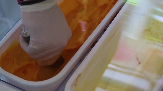 Closeup view of hand of man serving ice cream at confectionery shop.