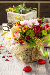 Background wedding or Valentine's Day. Basket bouquet of roses and chrysanthemums on a vintage wooden background.