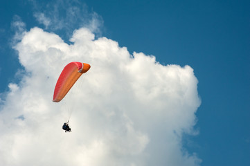 Alone paraglider flying in the blue sky against the background of clouds. Paragliding in the sky on...
