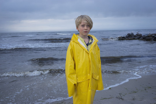 A young boy at the beach in wet weather gear