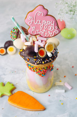 Easter freak shake decorated with Easter bunny gingerbread on grey background