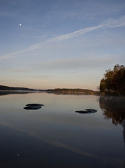 Rocks and moon reflecting in a calm lake, Bromma Stockholm, sweden