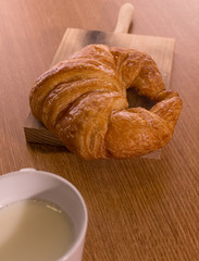 croissant with glass of milk on wooden board