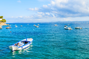 Fototapeta na wymiar BOL PORT, BRAC ISLAND - SEP 8, 2017: White fishing boat on blue sea and beautiful sunny sky with white clouds in Bol port, Brac island, Croatia.