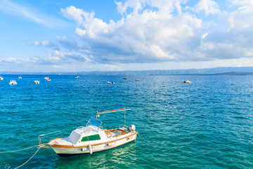 Naklejka na ściany i meble White fishing boat on blue sea and beautiful sunny sky with white clouds in Bol port, Brac island, Croatia
