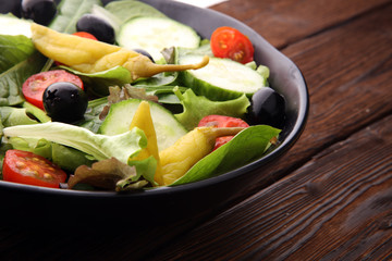 bowl of salad with vegetables and greens, with tomato, cucumber and onions.