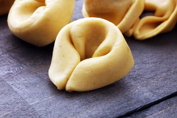 Raw cheese filled tortellini pasta on wooden background