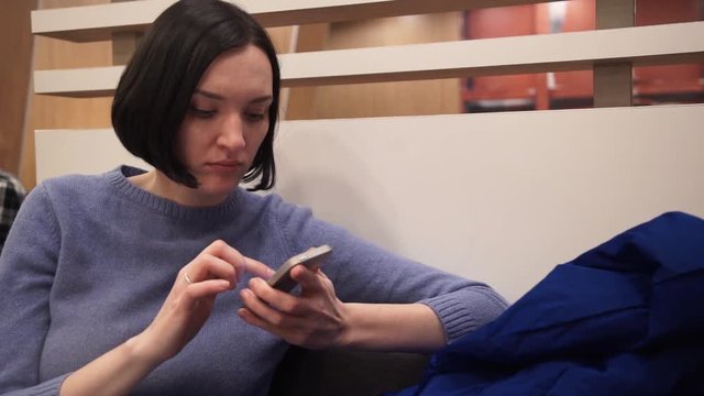 Portrait of young attractive woman using smartphone sitting in cafe.