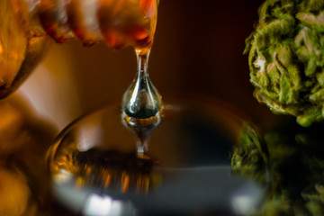 Medical Oil Drop of Cannabis - brown apothecary jar with oil drop and marijuana flower on the brown...