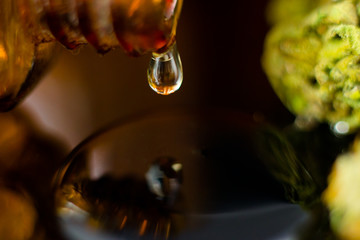 Medical Oil Drop of Cannabis - brown apothecary jar with oil drop and marijuana flower on the brown...